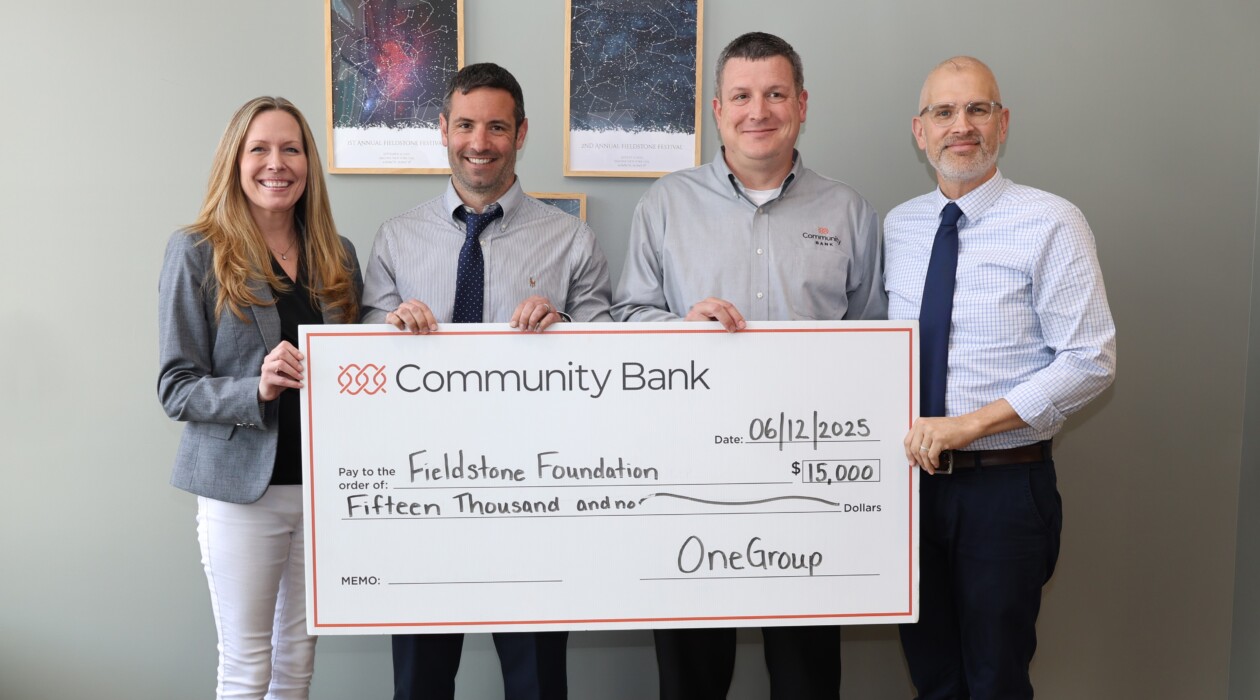 Four representatives of Fieldstone Foundation, OneGroup and Community Bank hold a check for $15,000.